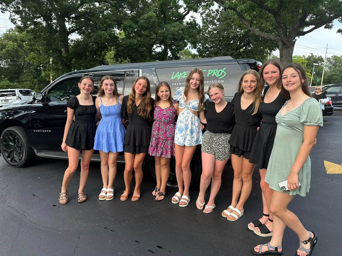 Lake Ride Pros luxury transportation fleet lined up at Lake of the Ozarks including limo bus, Rescue Squad truck, SUVs, and Mercedes Sprinter vans with lake view in background